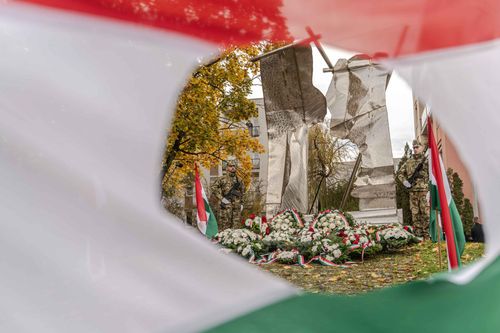 Lyukas zászló mögötte emlékmű és koszorúk